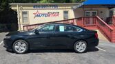 Side view of a black Chevrolet Malibu parked in front of the Atlanta Auto Star dealership with a blue canopy.