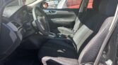 Front interior of a black sedan from the driver’s side showing the steering wheel, dashboard, center console, and black cloth seats.