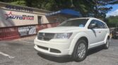 White SUV parked in front of Atlanta AutoStar dealership with a banner and pink-blue signage on the building exterior.