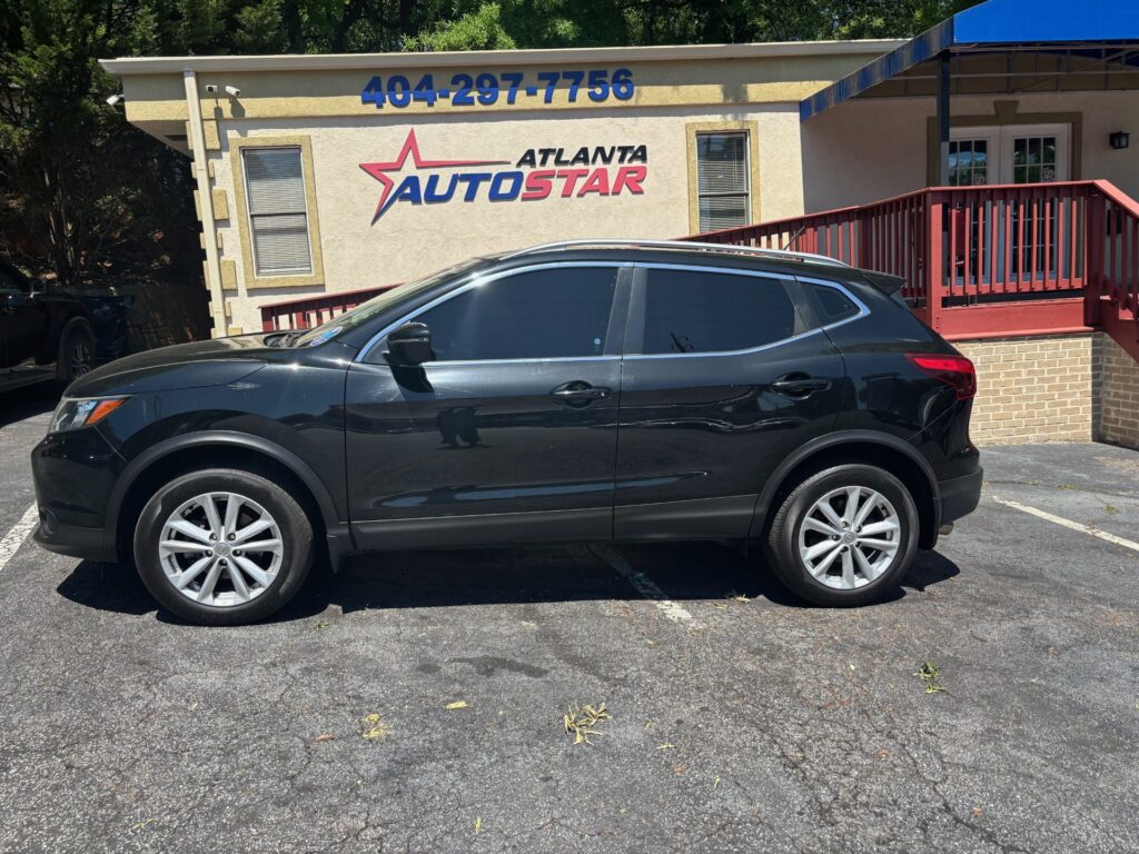 Black SUV parked in front of an Atlanta Auto Star dealership building with a red railing and blue sign above the entrance.