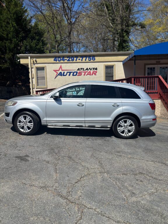 Silver SUV parked in front of a beige Atlanta Auto Star dealership building with a large blue phone number on the wall.