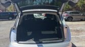 White SUV with tailgate open, revealing empty cargo area in a parking lot on a sunny day.
