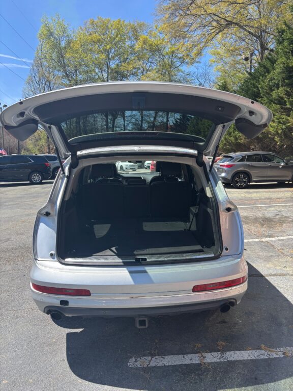 White SUV with tailgate open, revealing empty cargo area in a parking lot on a sunny day.