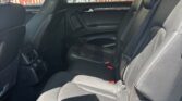 Rear interior of a black leather SUV, three-seat row with headrests and red seatbelt buckles.