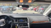 Interior of a car showing the dashboard, center console, gear shifter, and a mounted infotainment screen while parked in a lot.