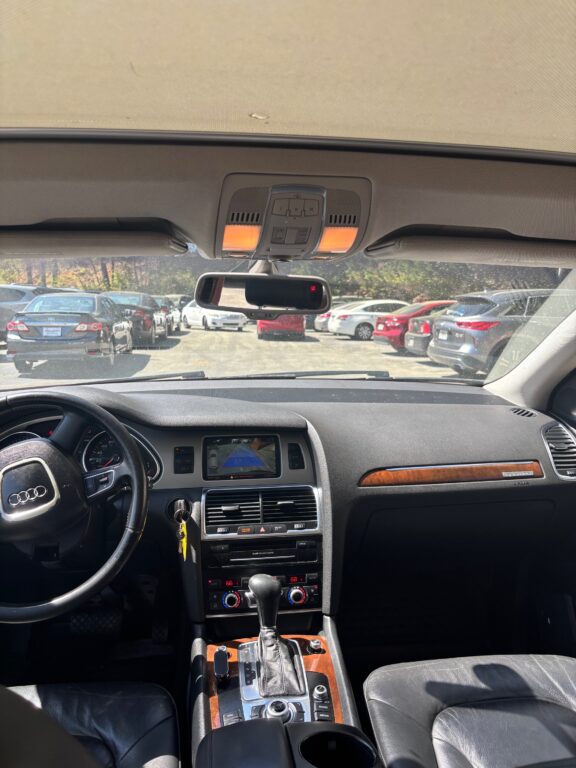 Interior of a car showing the dashboard, center console, gear shifter, and a mounted infotainment screen while parked in a lot.