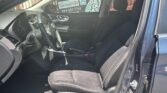 Interior view of a dark blue sedan from the open driver's side door, showing black cloth front seats, steering wheel, dashboard, and center console.