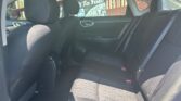 Back seat of a dark cloth interior car with three seats, headrests, and visible seat belts.