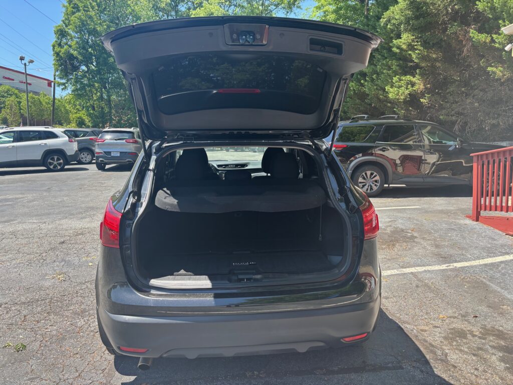 Dark SUV with the hatch raised, showing an empty cargo area in a sunny parking lot.