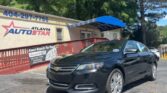 Black Chevrolet sedan parked in front of the Atlanta AutoStar dealership with a blue awning and red railing.