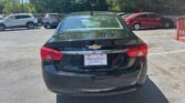 Rear view of a black Chevrolet sedan parked in a lot, dealership plate frame visible on the bumper.