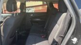 Back seat of a dark SUV with three cushions, headrests, and visible seat belts; sunlight inside.