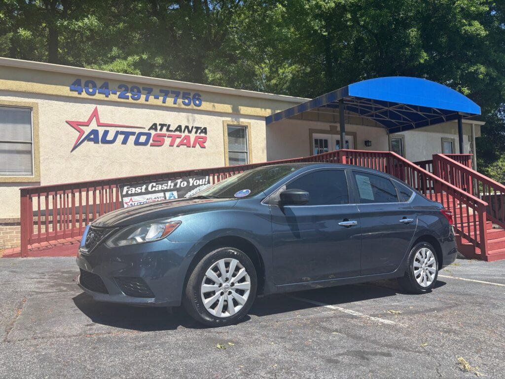 Blue sedan parked in front of the Atlanta AutoStar dealership, with a red wooden ramp and blue awning extending from the building.