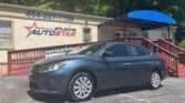 Blue sedan parked in front of the Atlanta AutoStar dealership, with a red wooden ramp and blue awning extending from the building.
