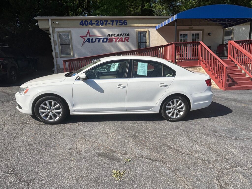 White four-door sedan parked in front of Atlanta AutoStar dealership with red stairs and a blue awning.