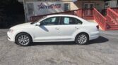 White four-door sedan parked in front of Atlanta AutoStar dealership with red stairs and a blue awning.