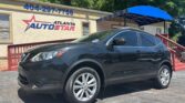 Black SUV parked outside a beige Atlanta AutoStar dealership with blue signboard and a red railing staircase behind it.