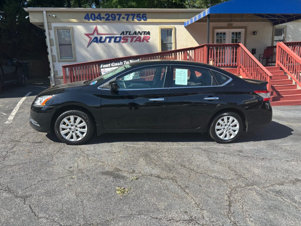 Black four-door sedan parked in front of the Atlanta Auto Star dealership building with a beige exterior and red railing.