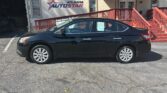Black four-door sedan parked in front of the Atlanta Auto Star dealership building with a beige exterior and red railing.