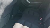 Back seat area of a dark cloth sedan, rear doors, and seat belts visible in daylight outside the window.