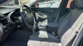 Interior view of a gray sedan showing the driver's seat, steering wheel, center console, and front passenger seat from the passenger side window view.