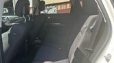 Rear passenger area of a black fabric SUV with two front seats, headrests, and visible seat belts in daylight outside the window
