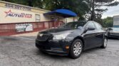 Front of an Atlanta Auto Star dealership with a blue curved canopy and a dark sedan in the parking lot.