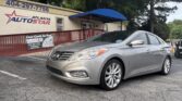 Silver sedan parked in front of Atlanta Auto Star dealership with a blue awning overhead and a banner on the railing behind it.