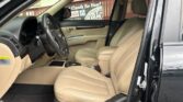 Front interior of a car with beige leather seats, steering wheel, and center console visible from the open driver’s door.