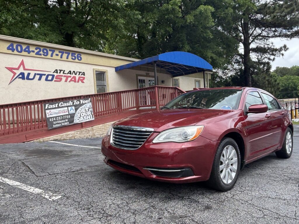 Red sedan parked in front of the Atlanta AutoStar dealership, blue awning overhead, with the phone number 404-297-7756 on the building sign.