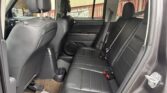 Dark leather back seat area of an SUV, showing two headrests, seat belts, and a center cup holder/console.