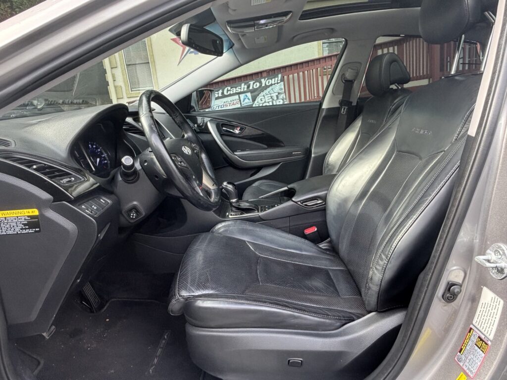 Black leather front seats and dashboard of a Hyundai Azera, viewed from the driver's door open.