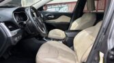 Front interior of a Jeep with beige leather seats, steering wheel, and center console; view through the passenger door shows a red fence and a 'Fast Cash To You' banner outside.