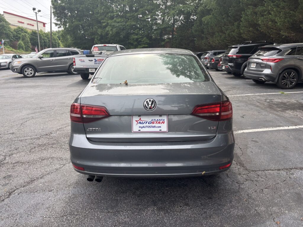 Rear view of a gray Volkswagen Jetta in a car dealership lot, with an Atlanta Autostar license plate frame.