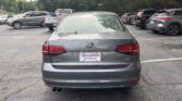 Rear view of a gray Volkswagen Jetta in a car dealership lot, with an Atlanta Autostar license plate frame.