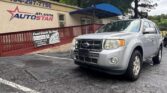 Silver Ford SUV parked diagonally in front of the Atlanta Auto Star dealership, beige storefront with a blue awning and red railing; visible signage includes the dealership name and a 'Fast Cash' poster.