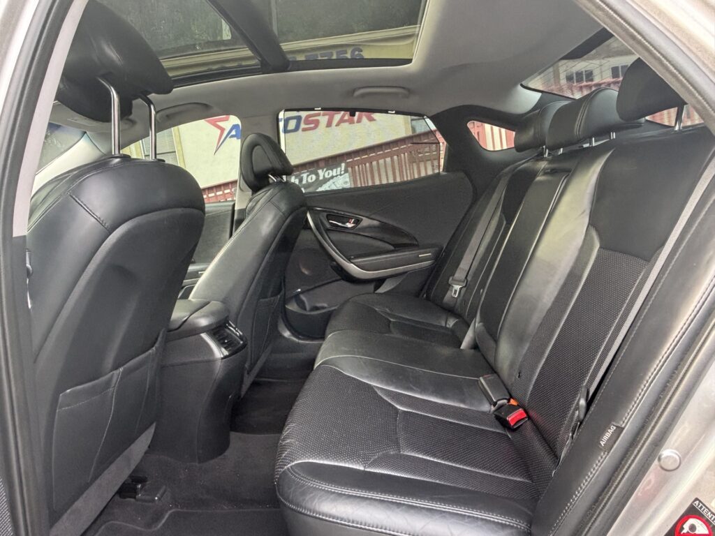 Rear interior of a black leather car with two row seats, sunroof, and headrests visible through open doors