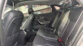 Rear interior of a black leather car with two row seats, sunroof, and headrests visible through open doors