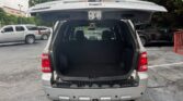 Rear view of a silver SUV with the hatch open, showing an empty cargo area in a parking lot.