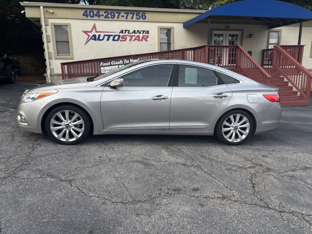 Silver four-door sedan parked in front of Atlanta Auto Star dealership with a blue canopy.