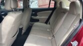 Rear passenger area of a beige fabric sedan showing three-seat bench, headrests, and seat belts
