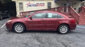Maroon four-door sedan parked in front of a beige building with an Atlanta Auto Star sign and a blue awning.