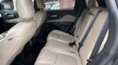 Beige leather SUV rear seating with three seats, headrests, and visible seat belts.