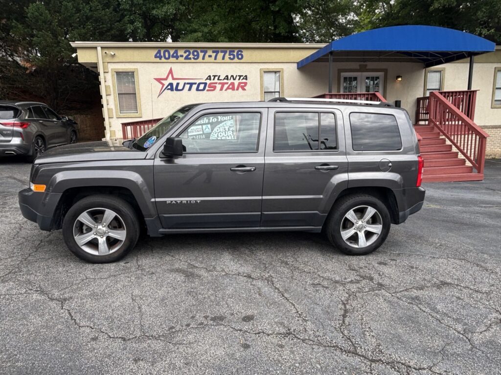Grey Jeep Patriot SUV parked in front of the Atlanta Auto Star storefront with a blue canopy.