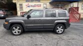 Grey Jeep Patriot SUV parked in front of the Atlanta Auto Star storefront with a blue canopy.