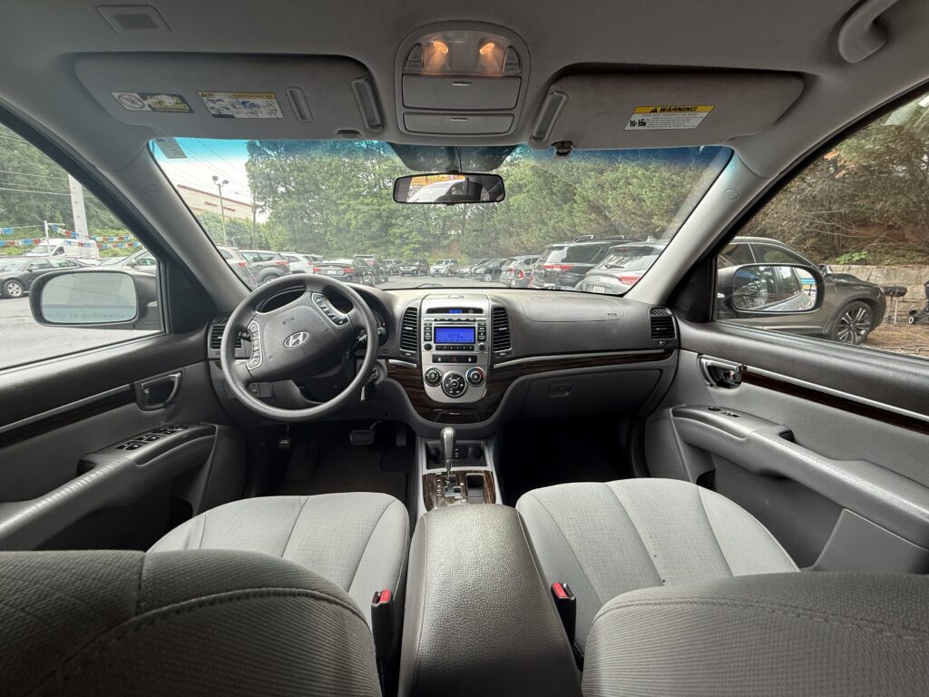 Interior of a car viewed from the back seat, showing steering wheel, center console, and front seats with gray upholstery