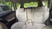 Rear interior of a beige SUV back seat with three seating positions, headrests, and visible seat belts.