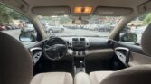 View from the back seat looking toward the front of a parked SUV, with the dashboard and center console visible and a busy car lot outside the windows.