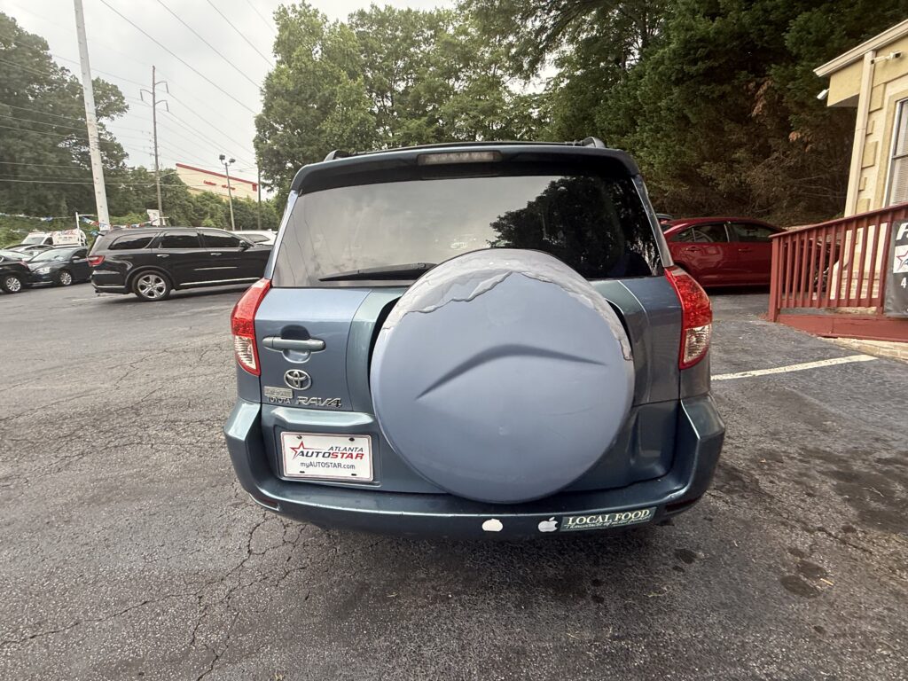 Rear of a blue Toyota RAV4 with a spare-tire cover in a parking lot; dealership plate frame reads ATLANTA AUTOSTAR.