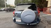 Rear of a blue Toyota RAV4 with a spare-tire cover in a parking lot; dealership plate frame reads ATLANTA AUTOSTAR.